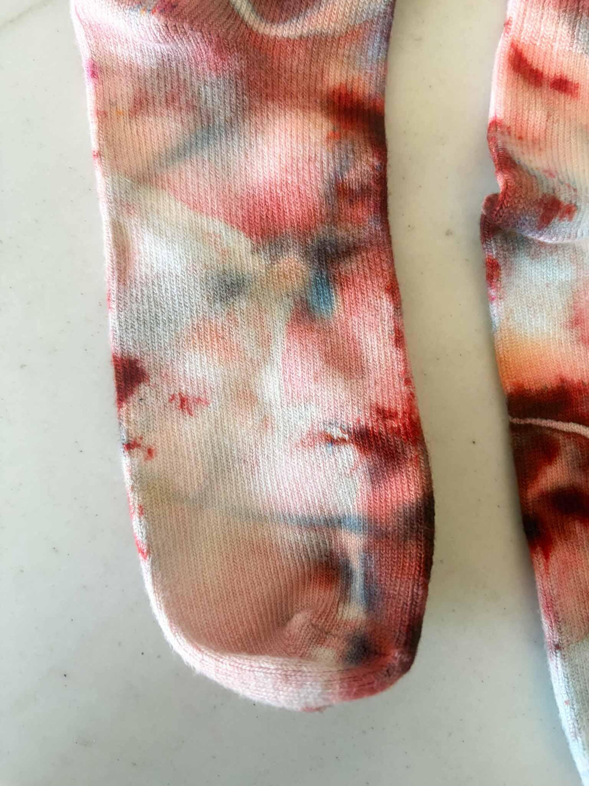 Close-up of sock toe and foot showing watercolor style Bloodmoon tie dye blend