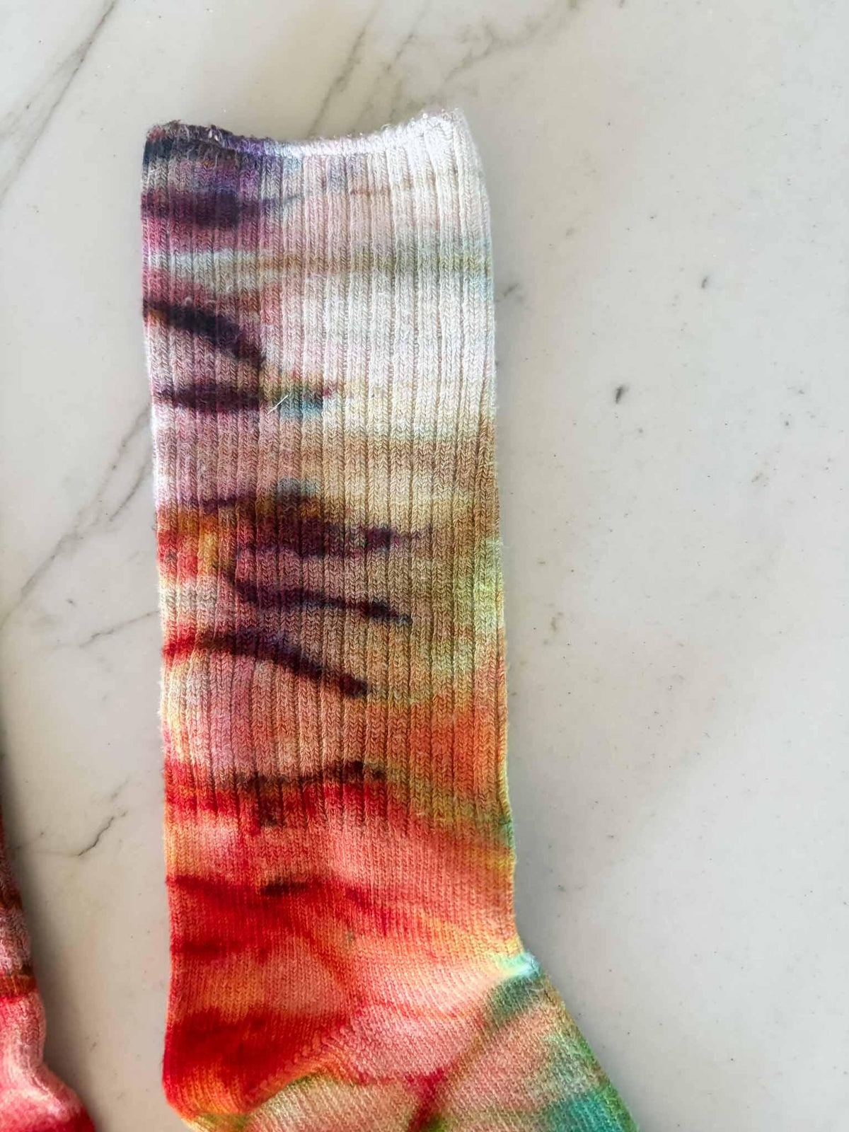 Close-up of sock leg showing purple to red to green ombre gradient
