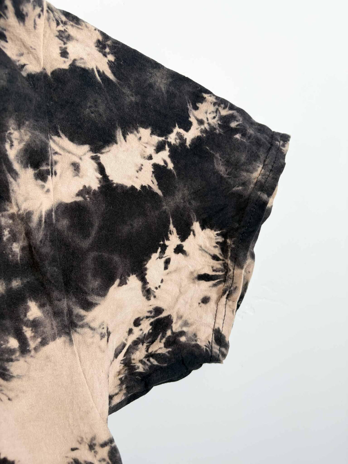 Close-up of sleeve showing reverse tie dye spiral rays in black and tan