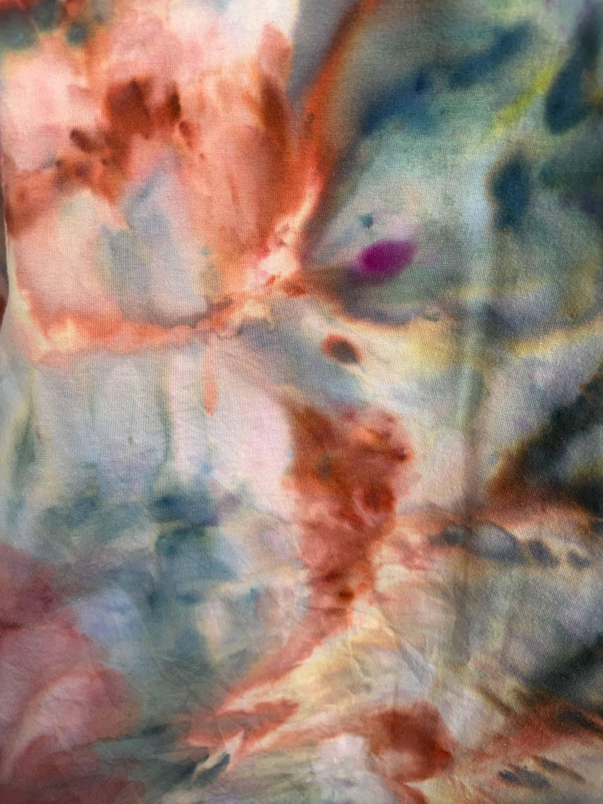 Close up of ice dye pattern showing rust, slate blue, and gold color blending on cotton fabric