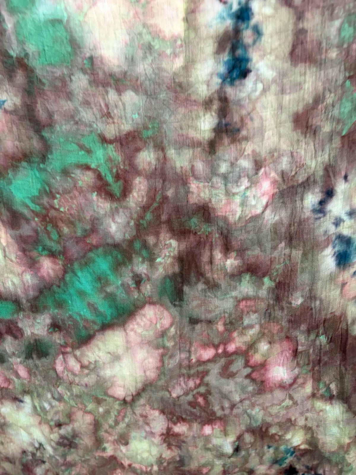 Close-up of ice dyed bamboo gauze with cloudy dusty rose and berry tones blending into bright jade green, with a streak of navy blue.